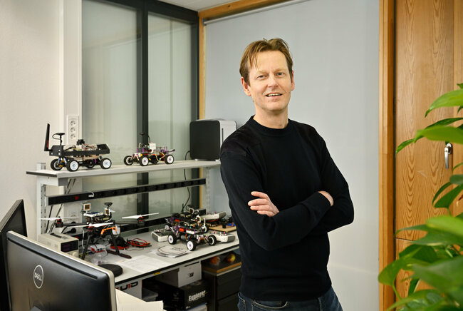 Part-time professor Henk Jan Bergveld. In the background, self-driving model cars used in the NXP Cup. Photo: Bart van Overbeeke