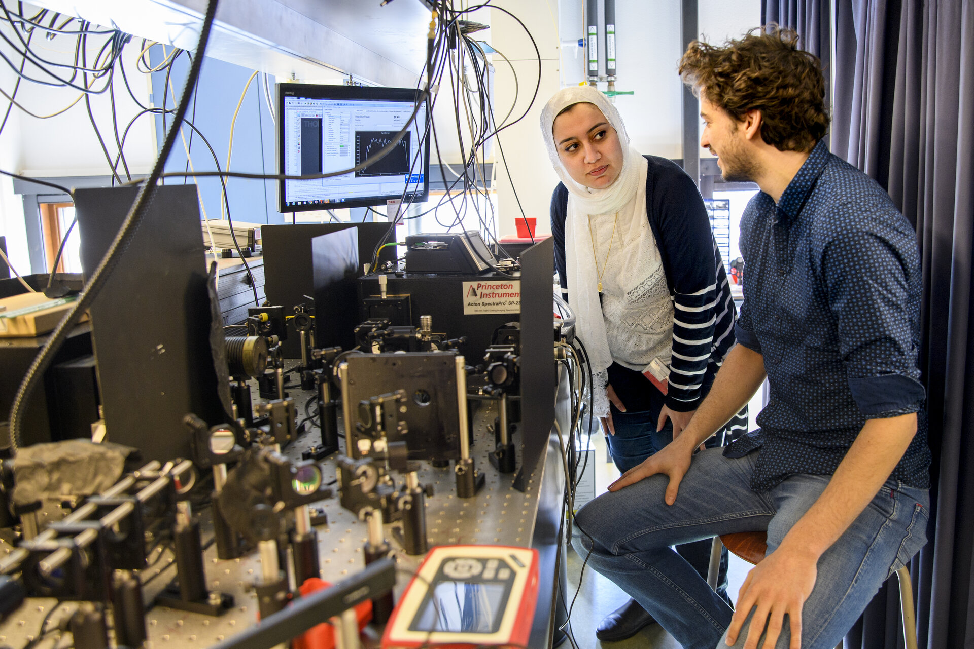 Shared first authors Elham Fadaly (left) and Alain Dijkstra (right) operating an optical setup to measure the light that is emitted. The emission from the hexagonal-SiGe alloy showed to be very efficient and suitable to start producing a silicon compatible laser. Photo: Sicco van Grieken, SURF.
