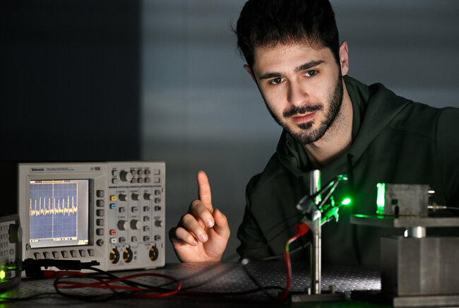 Onderzoeker Riccardo Ollearo laat zien hoe de fotodiode (rechts) het signaal opvangt van zijn vinger, en zo kan zien hoe snel zijn hart klopt (links). (Foto: Bart van Overbeeke)